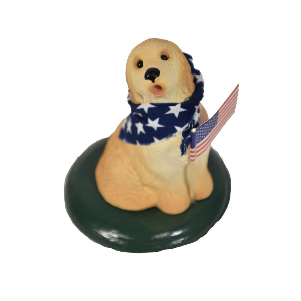  Patriotic golden retriever  figurine wearing a American flag scarf  and holding an American flag on a green base on a white background