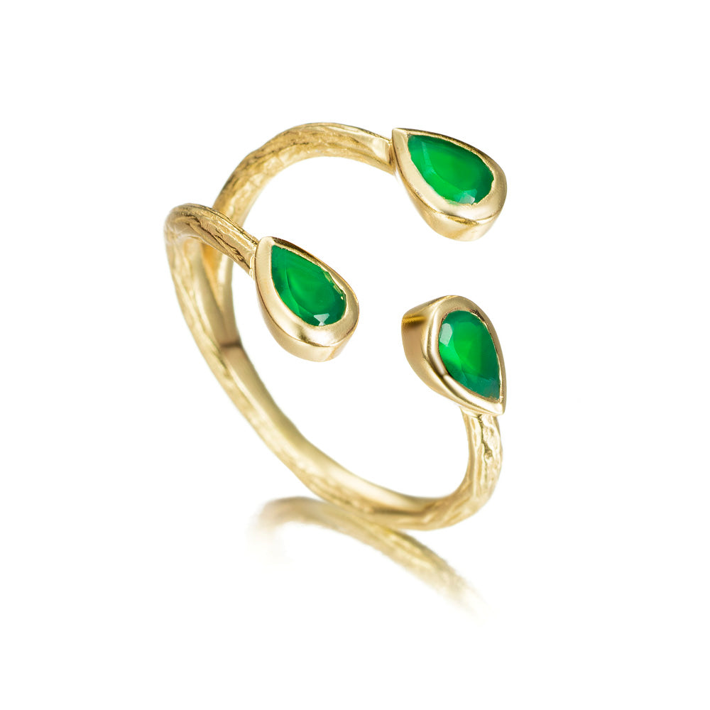 A gold open ring with three teardrop-shaped green gemstones, shown on a clean white background with a soft reflection.