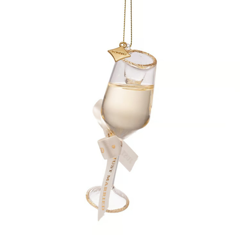A champagne flute-shaped hanging ornament with a gold rim, filled with pale gold liquid, featuring a white ribbon bow and a small gold tag that reads 'CHAMPAGNE'.