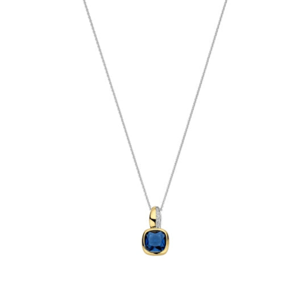 A delicate silver chain necklace with a cushion-cut blue gemstone pendant in a two-tone gold and silver bezel setting, shown against a plain white background.