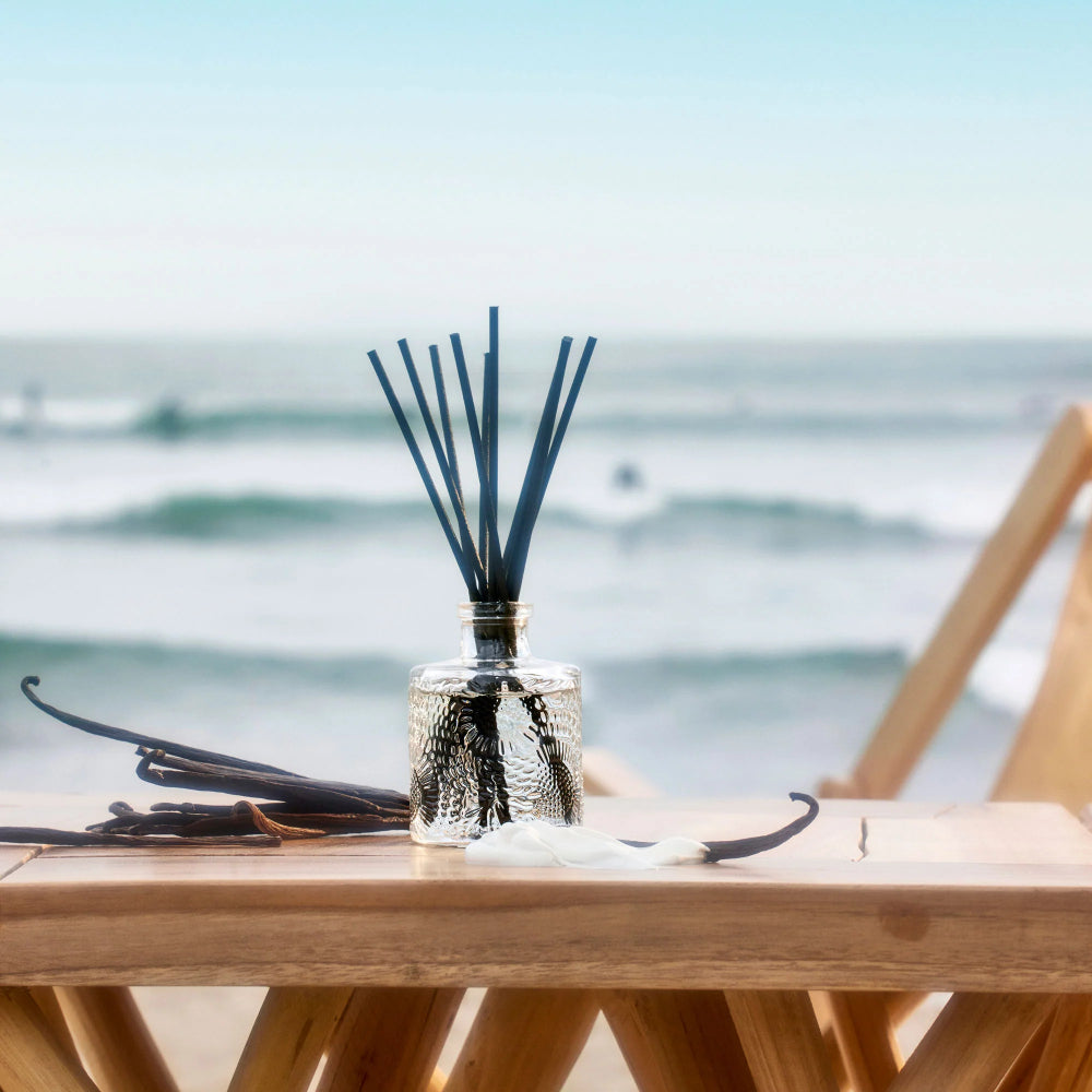 Diffuser with reeds on a table by the sea.