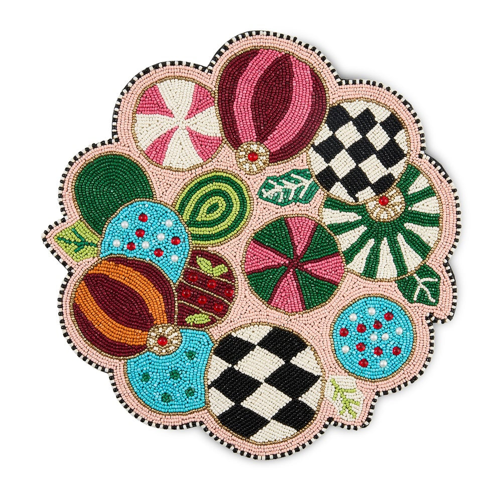 A circular beaded holiday placemat featuring a collection of colorful, stylized hot air balloons in various patterns like stripes, checkers, and dots, set against a light pink background with a black and white beaded border.