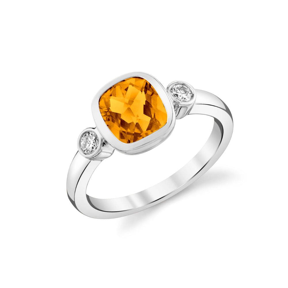 Silver ring with a yellow gemstone and smaller clear stones on a white background