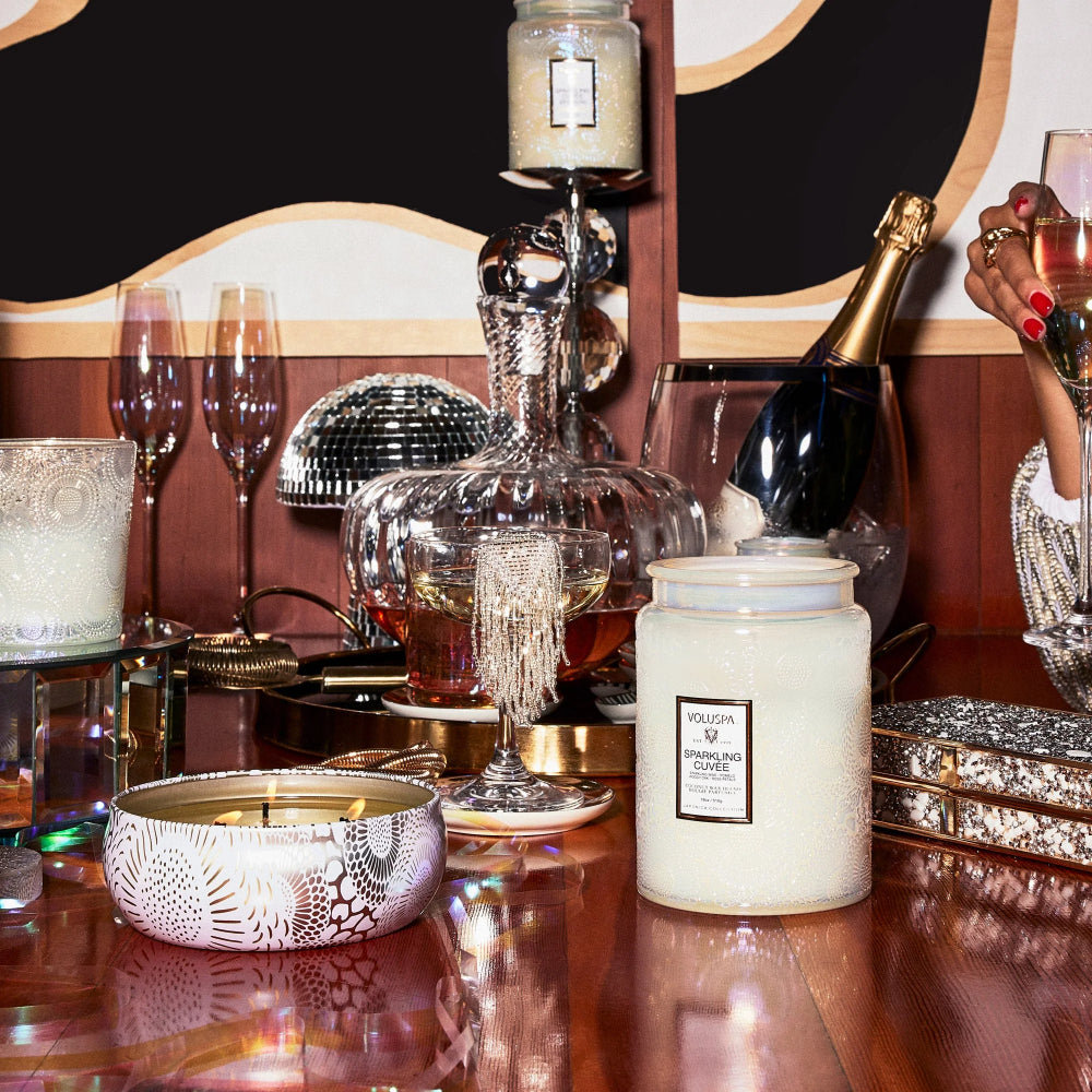 Large white Spakling Cuvee candle on a brown table with festive decor 