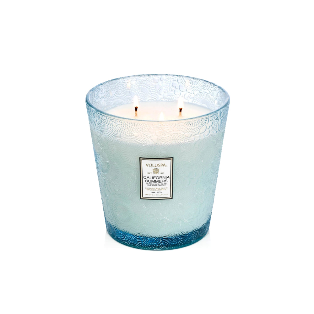 A Volga Group Californian Tranquility scented candle in a textured light blue glass jar with two lit wicks, shown on a clean white background.