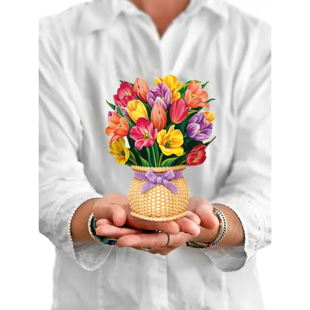 Person holding a colorful bouquet of flowers in a woven basket.