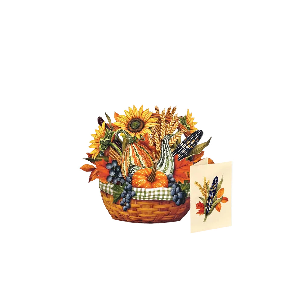 An autumn harvest-themed basket arrangement featuring sunflowers, pumpkins, corn, grapes, and wheat, shown with a small matching greeting card on a plain white background.