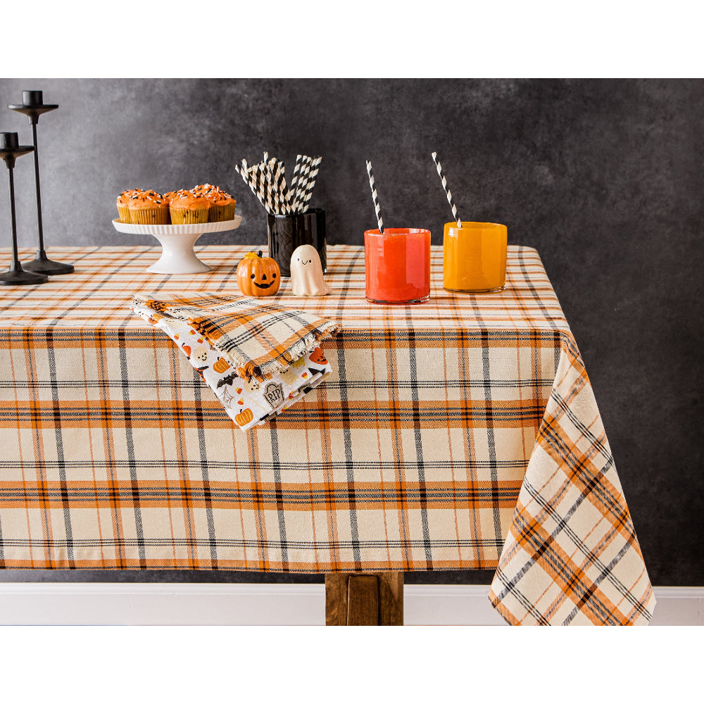Table setting with plaid tablecloth, Halloween-themed napkins, and drinks.