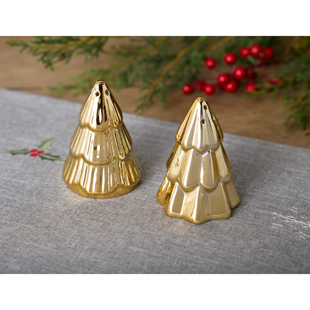 Two gold Christmas salt & pepper shakers on a textured surface with greenery and berries in the background.