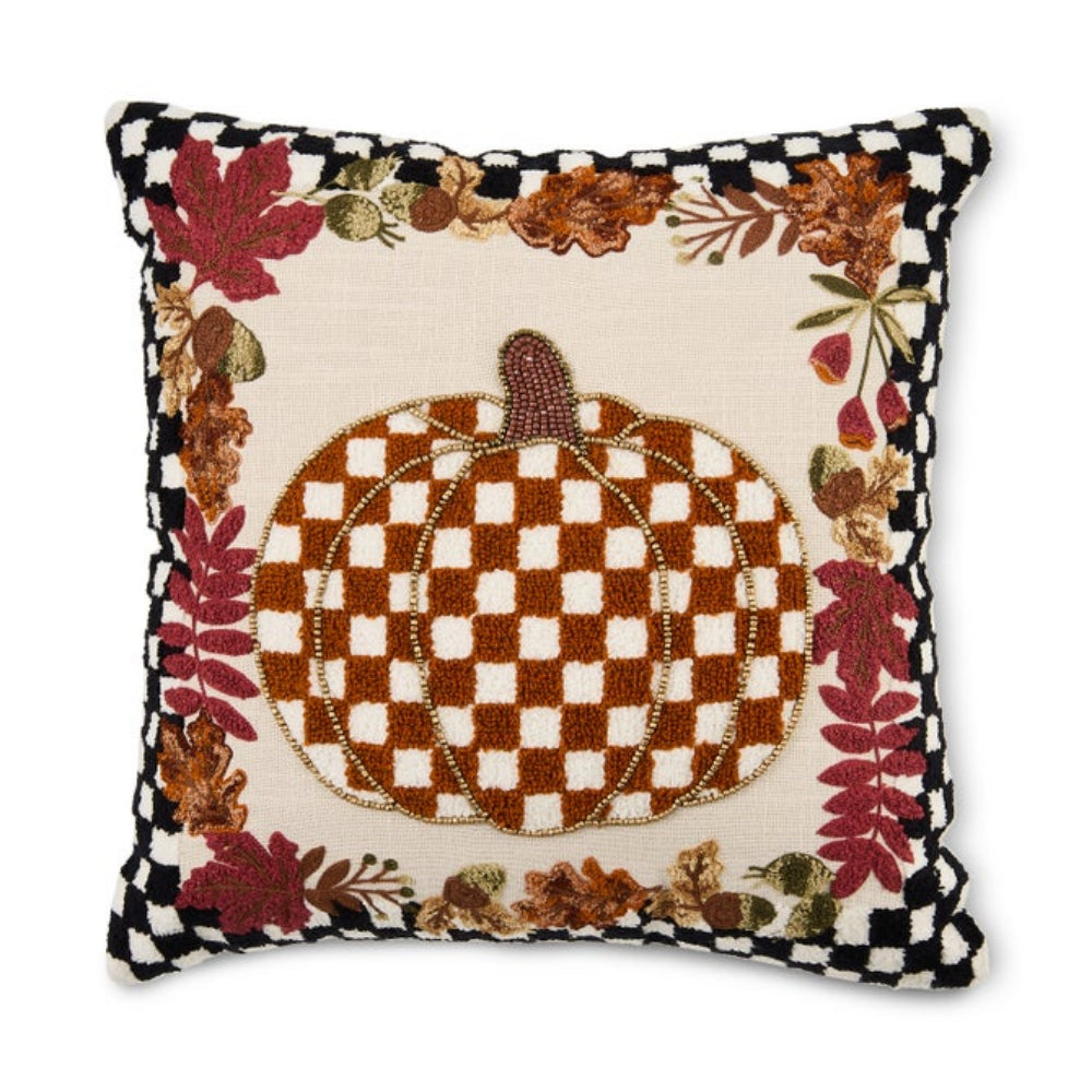 A square decorative throw pillow with an autumn theme, featuring a central brown and cream checkered pumpkin surrounded by a border of red and brown leaves, autumn foliage, and a black-and-cream checkered edge.