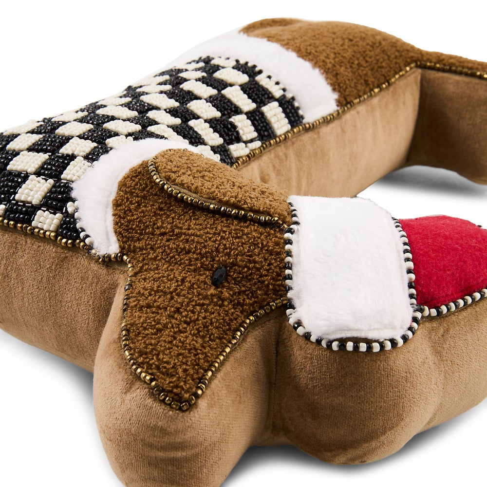 A close-up of a dachshund pillow in brown fabric with a black-and-white checkered patterned section, white faux-fur trim, and a red inner mouth detail, photographed on a white background.