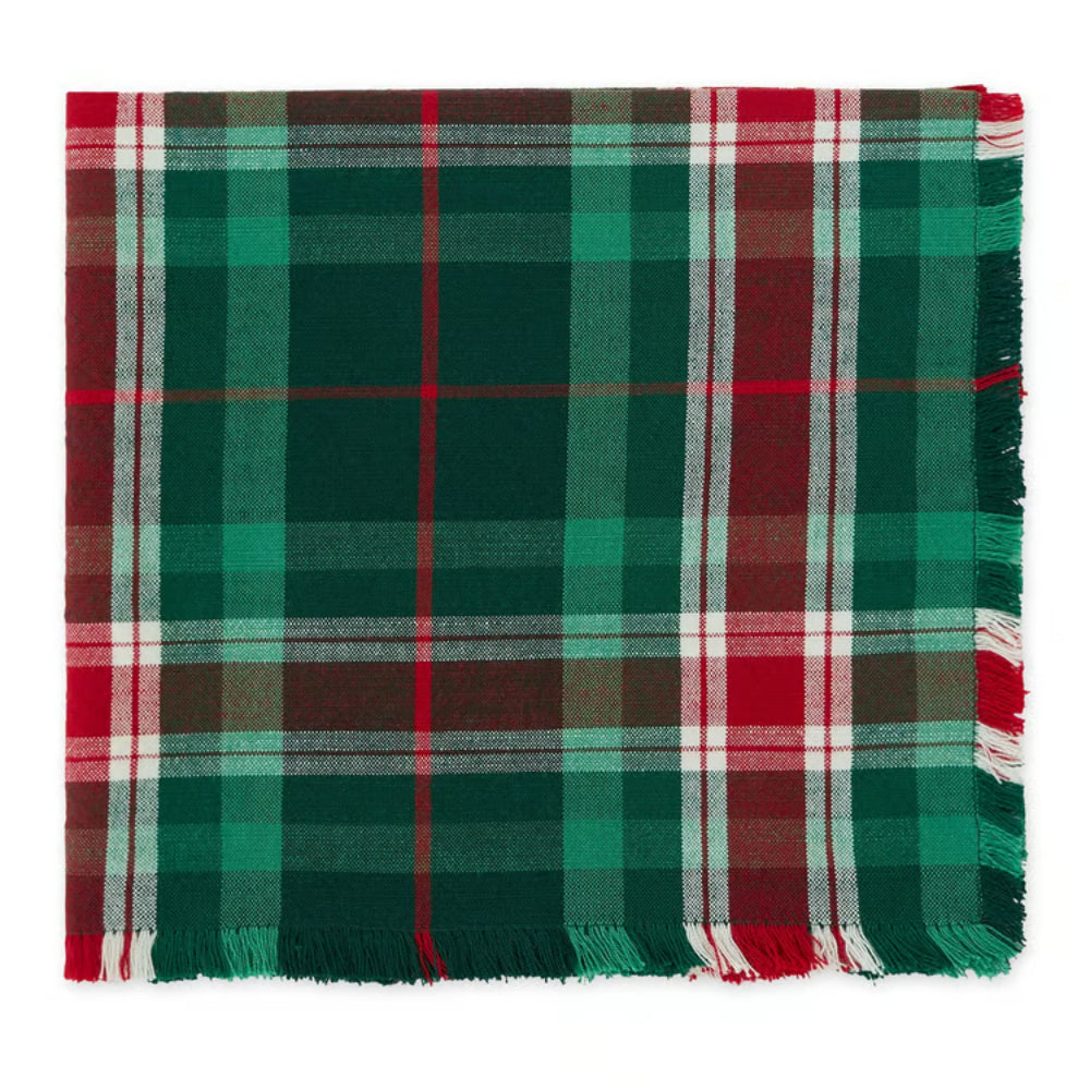 A square plaid napkin with fringe on the edges, featuring a festive holiday pattern of dark green, red, white, and brown stripes.