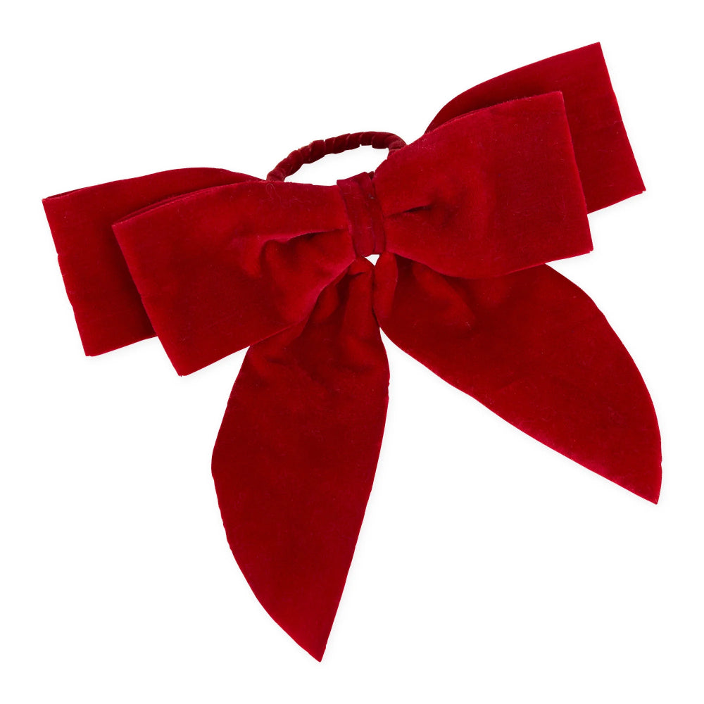 A red velvet hair bow headband with a large bow and long ribbon tails, attached to a thin red elastic band, shown on a plain white background.