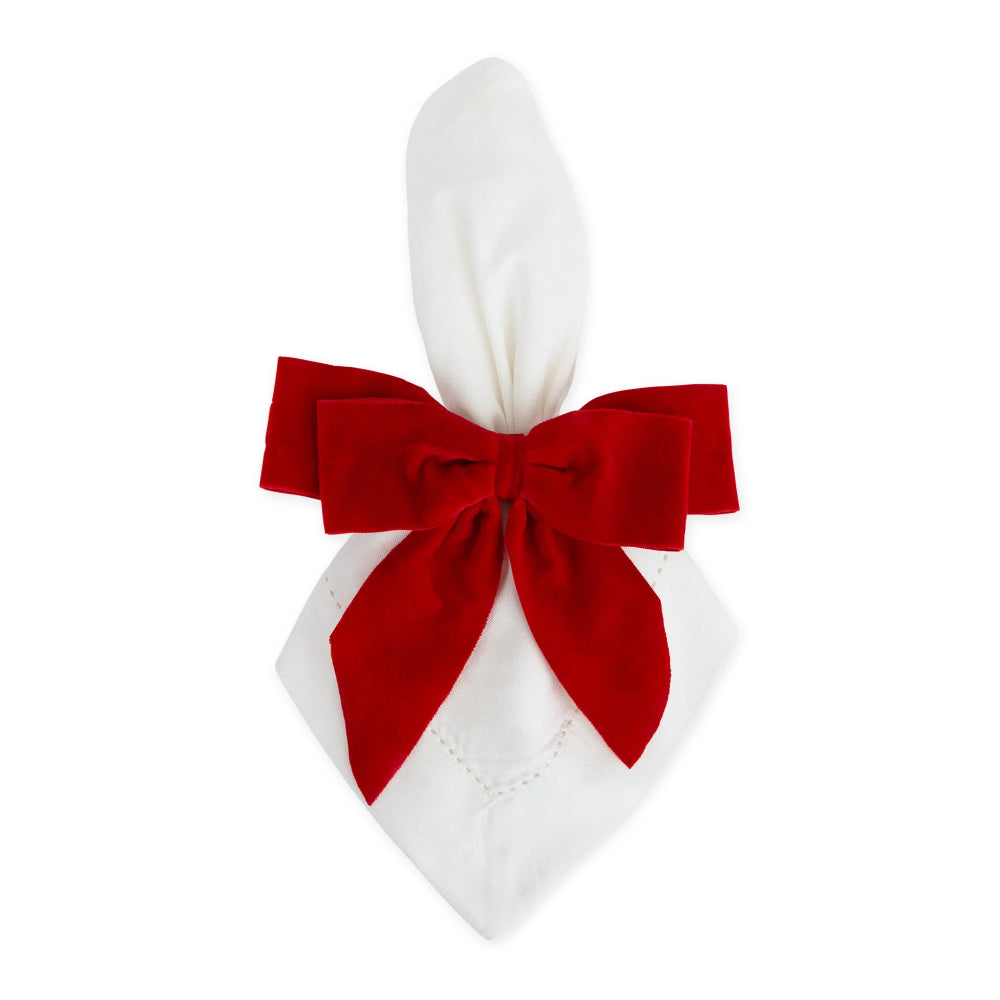 A white napkin folded into a bunny ears shape and tied with a large red velvet bow, shown on a plain white background.