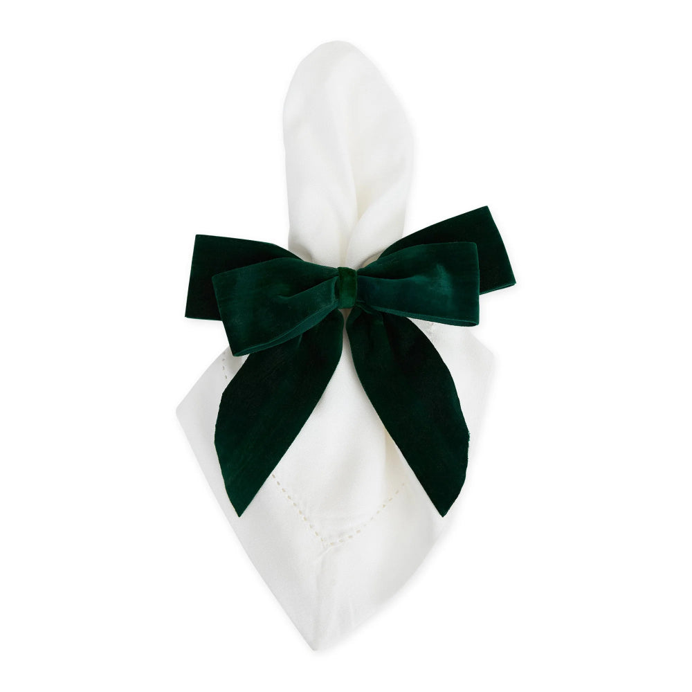 A white folded napkin tied with a large dark green velvet bow, shown on a plain white background.