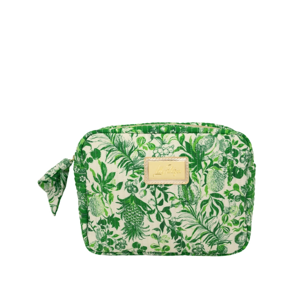 A rectangular zippered pouch with a green tropical botanical print on a cream background, featuring a small gold-tone metal brand plaque on the front and a matching fabric wristlet strap on the left side.