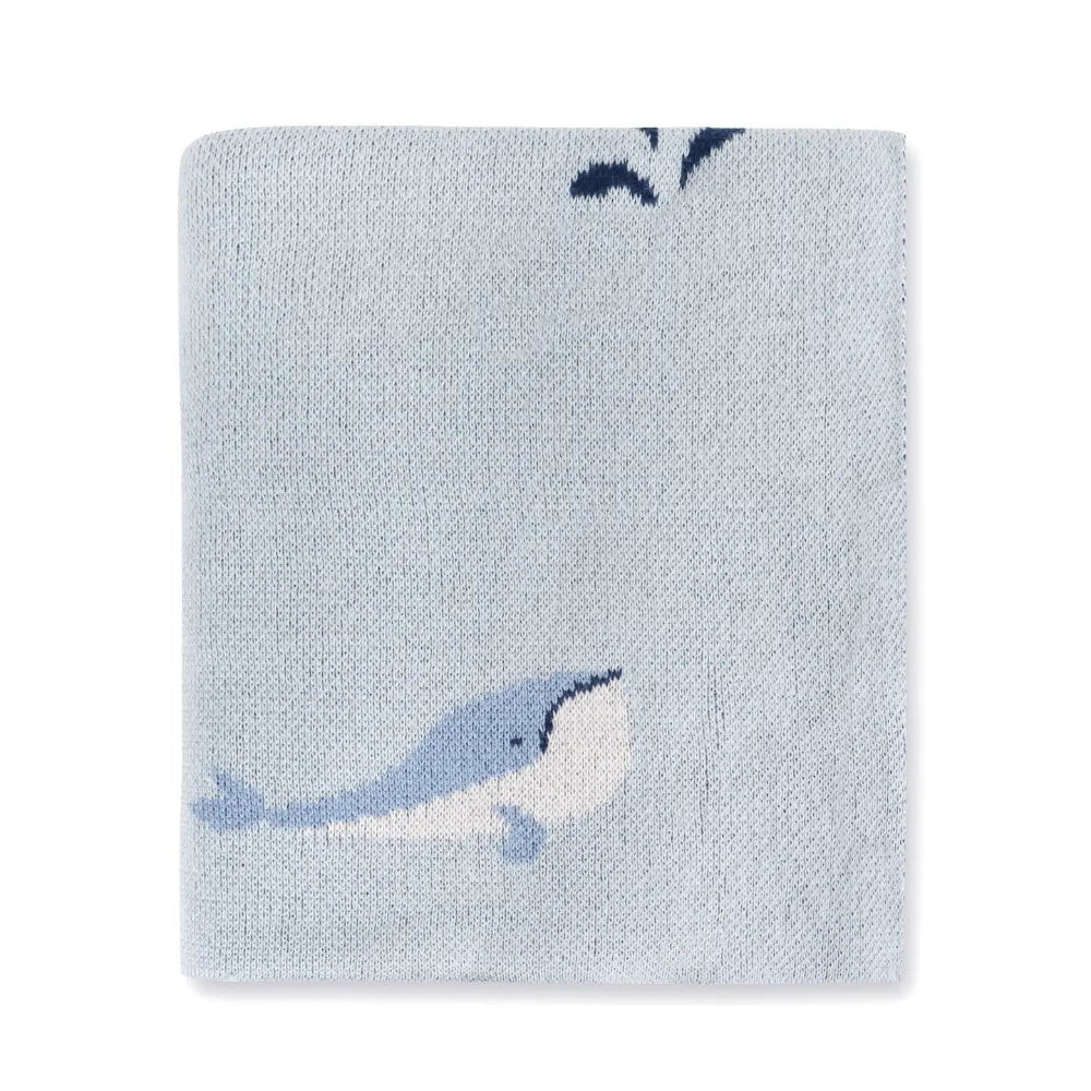 Knitted blanket with whale design on a light blue background.