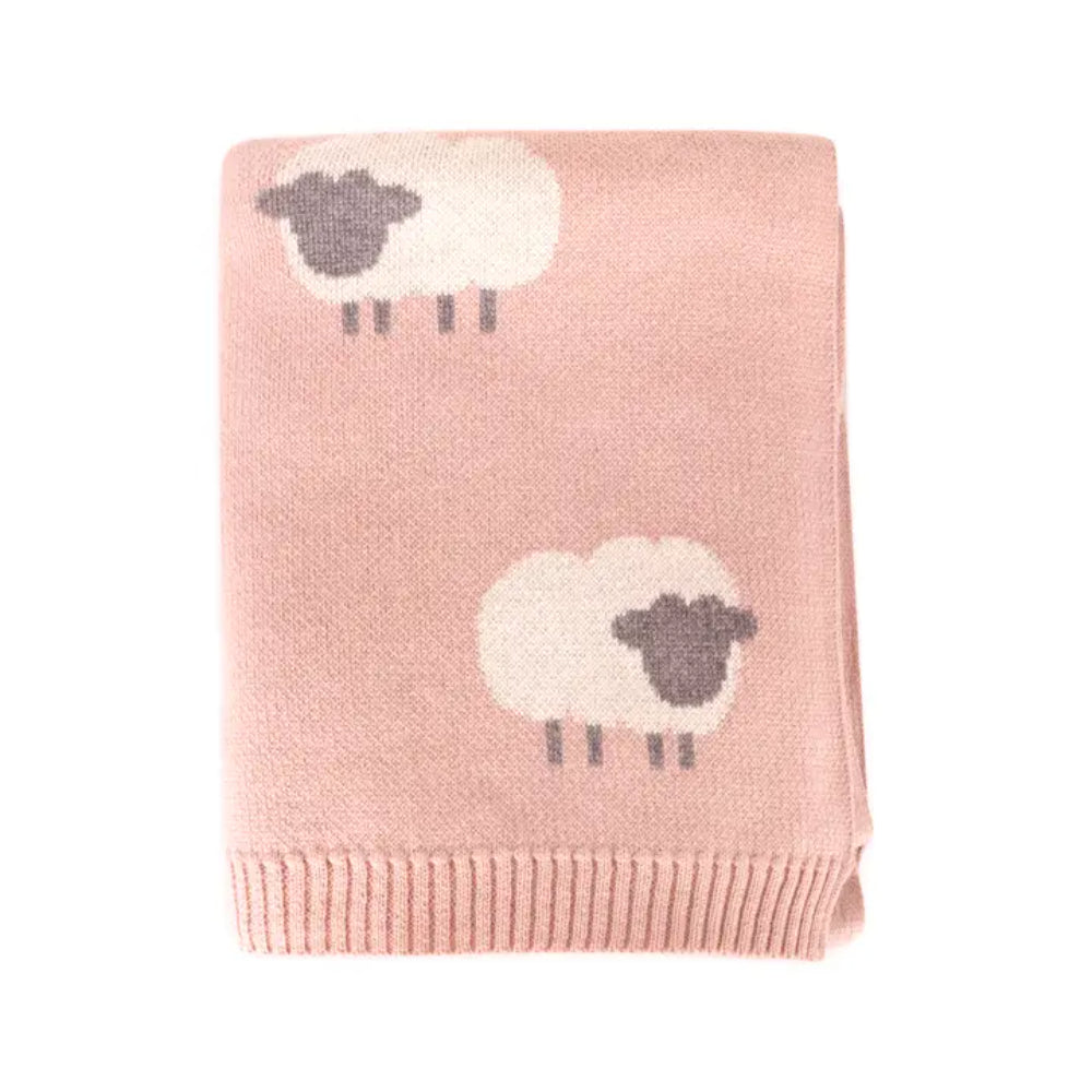 Pink knitted blanket folded with a lamb pattern on a white background.