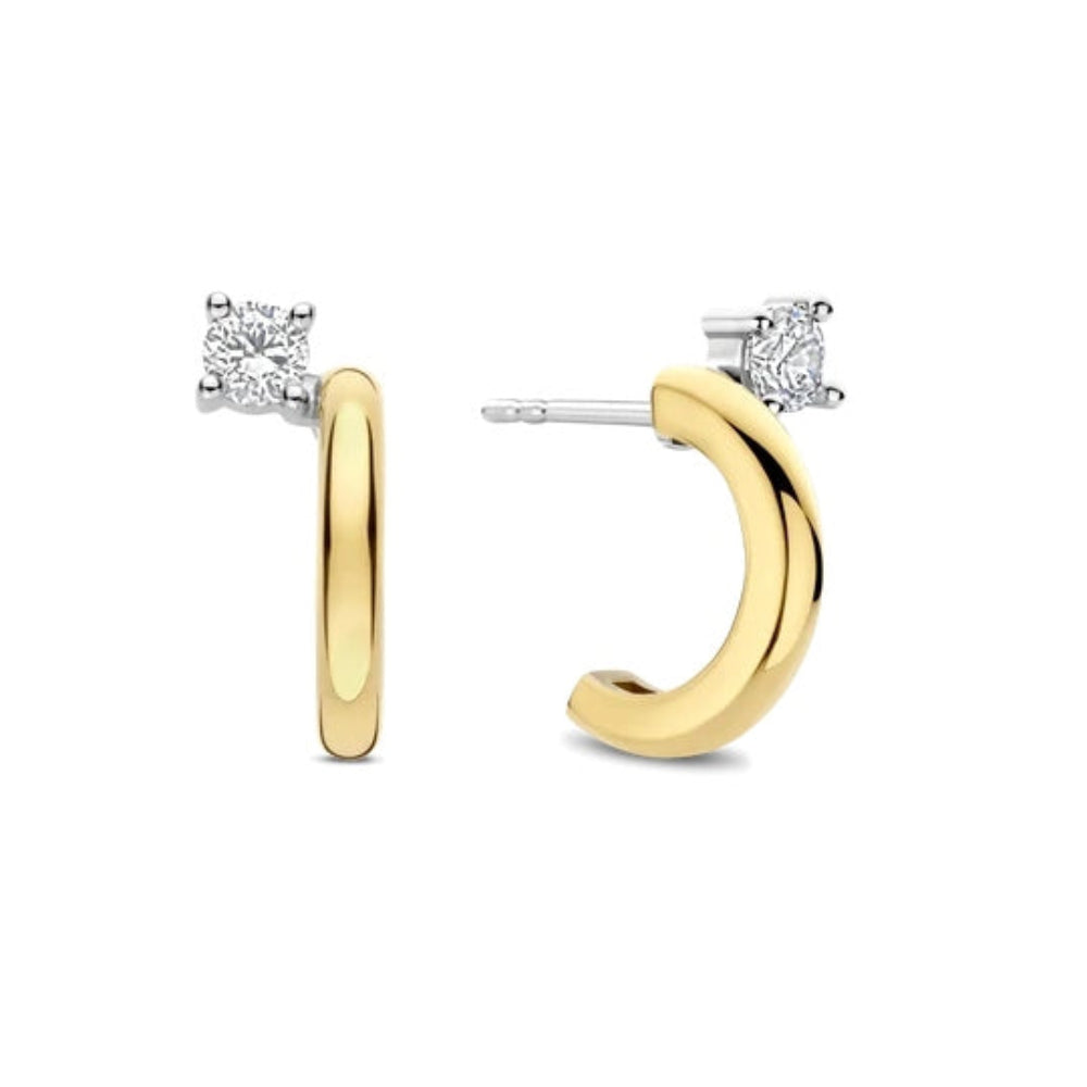A pair of gold and silver huggie hoop earrings, each featuring a small square-cut clear gemstone in a prong setting. One earring is shown from the front, displaying the polished gold band, and the other is shown from the side/back, displaying the silver post and the gold hoop.