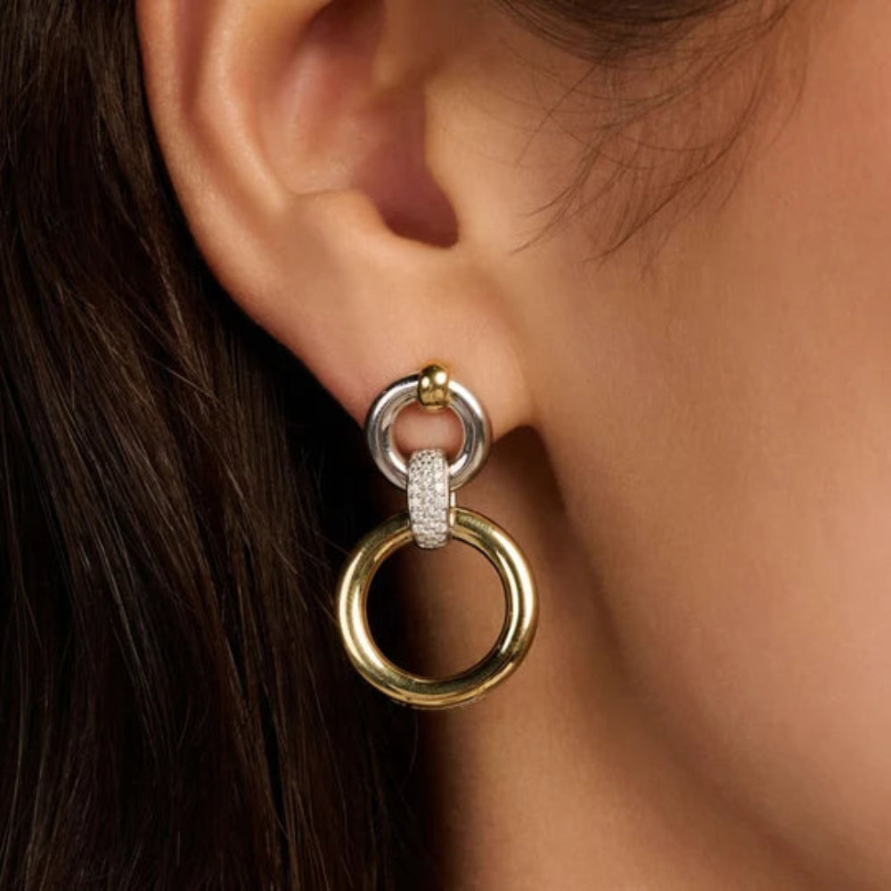 A close-up of a model's ear wearing a two-tone gold and silver hoop earring with a pavé-set accent.
