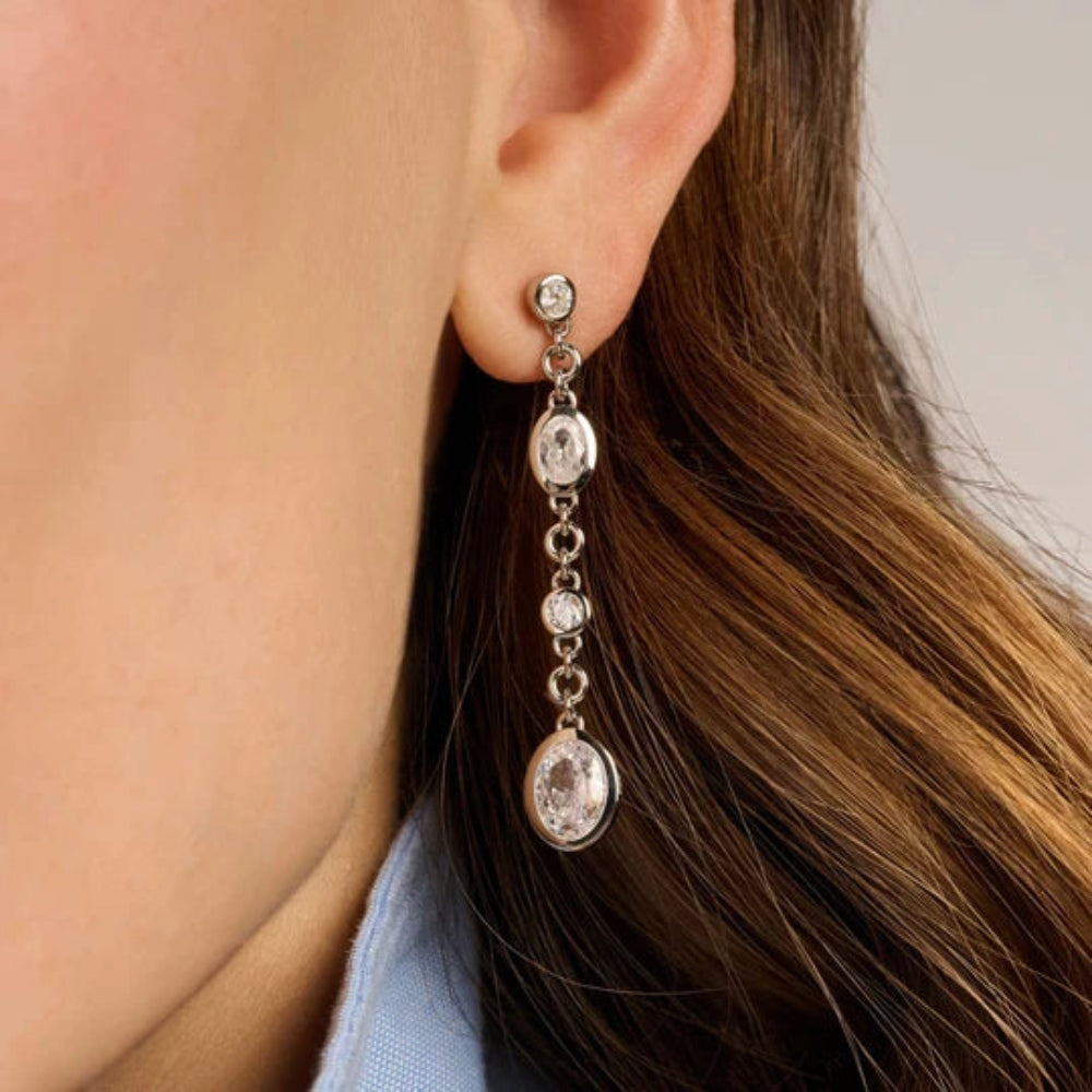 woman wearing Silver oval drop earrings with multiple stones in different shapes and sizes arranged vertically