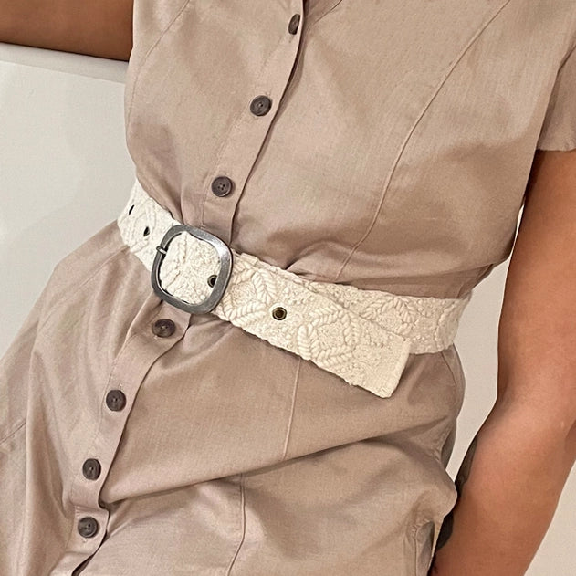 Person wearing a beige shirt with a lace belt and a neutral background
