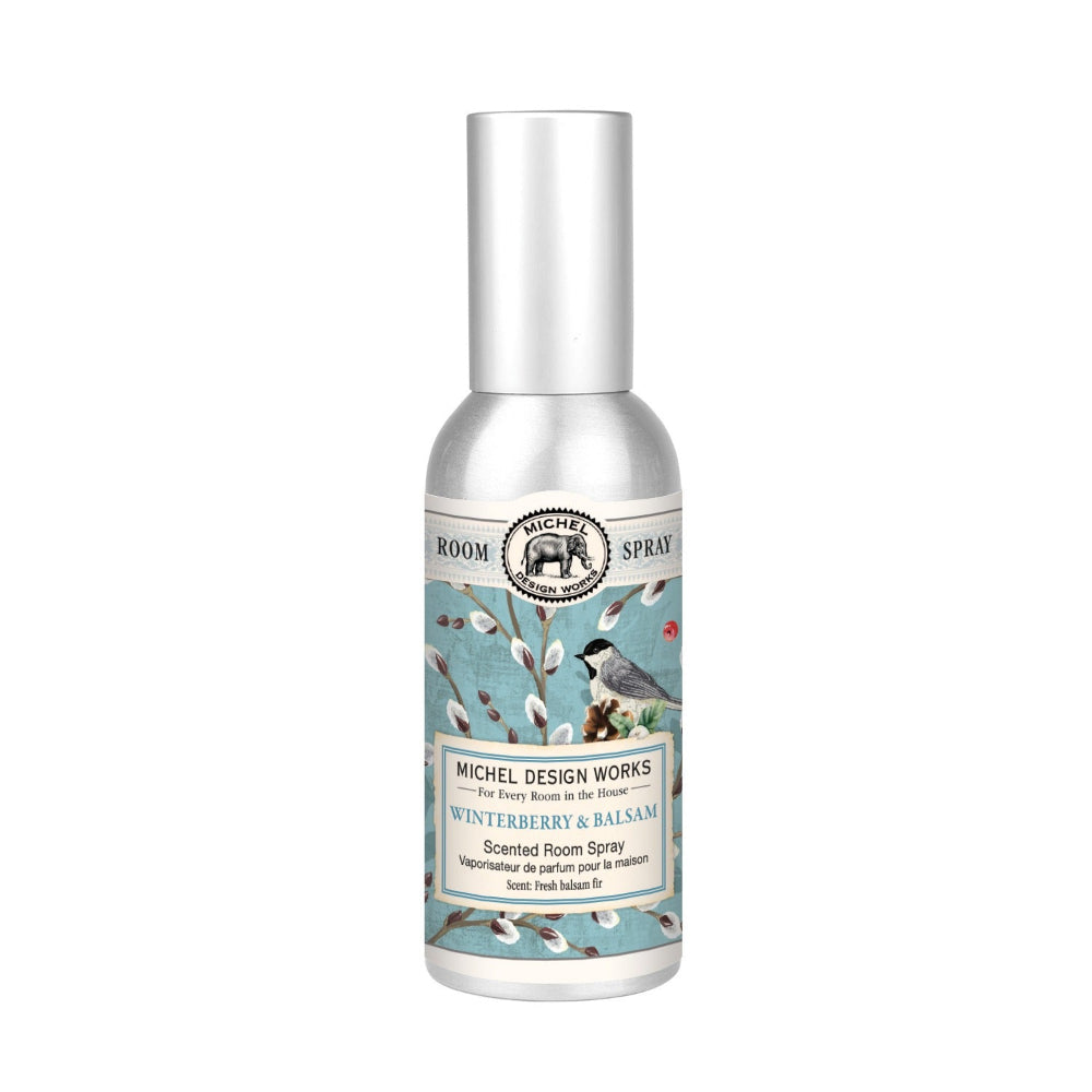 A bottle of Michel Design Works Winterberry & Balsam Room Spray with a label featuring birds and holly.
