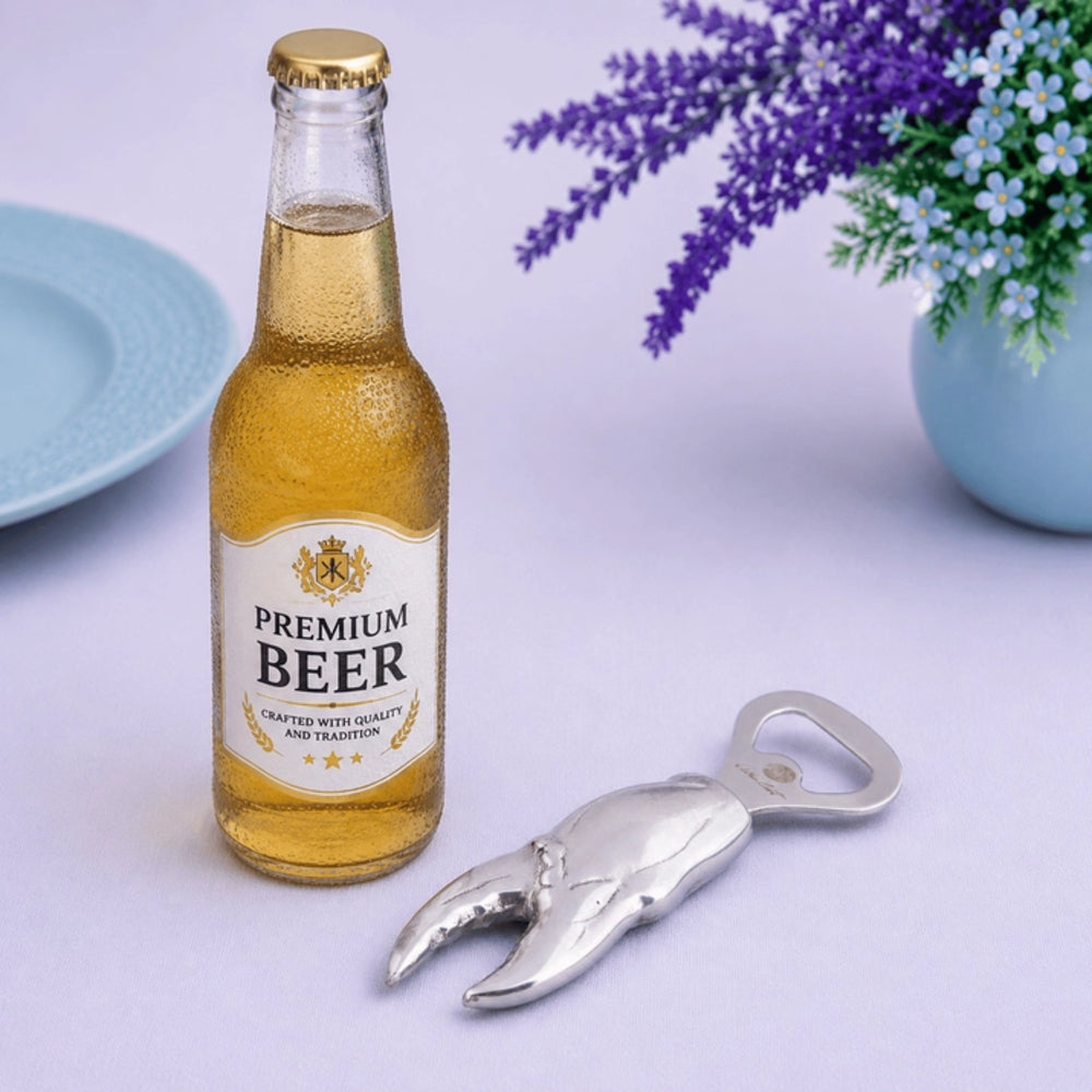 Bottle of premium beer with a claw-style bottle opener on a light surface with flowers in the background.