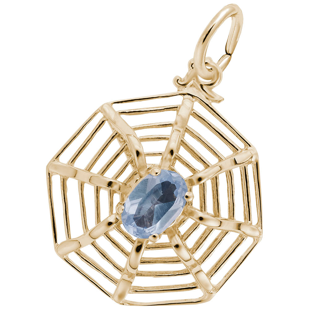 Gold spider web shaped charm with a blue gemstone on a white background