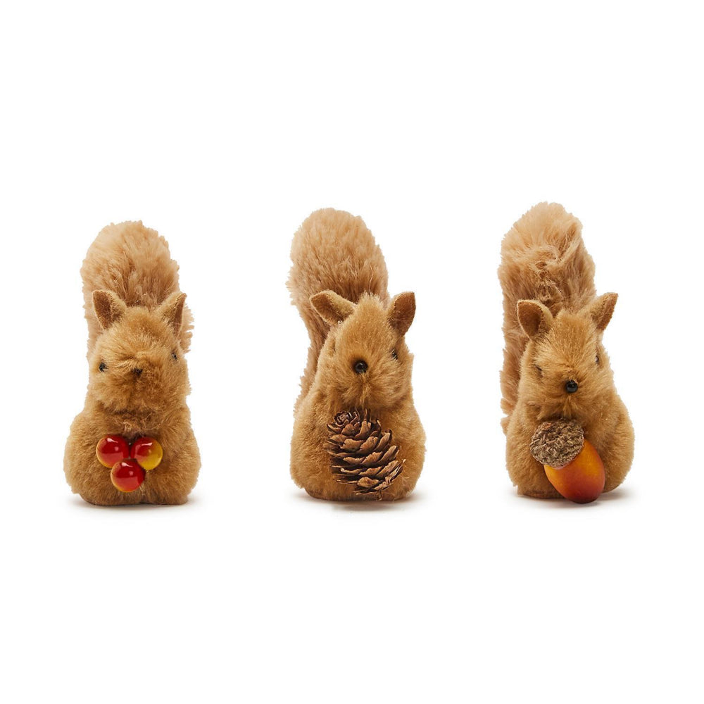 Three plush squirrels holding pine cones and apples on a white background