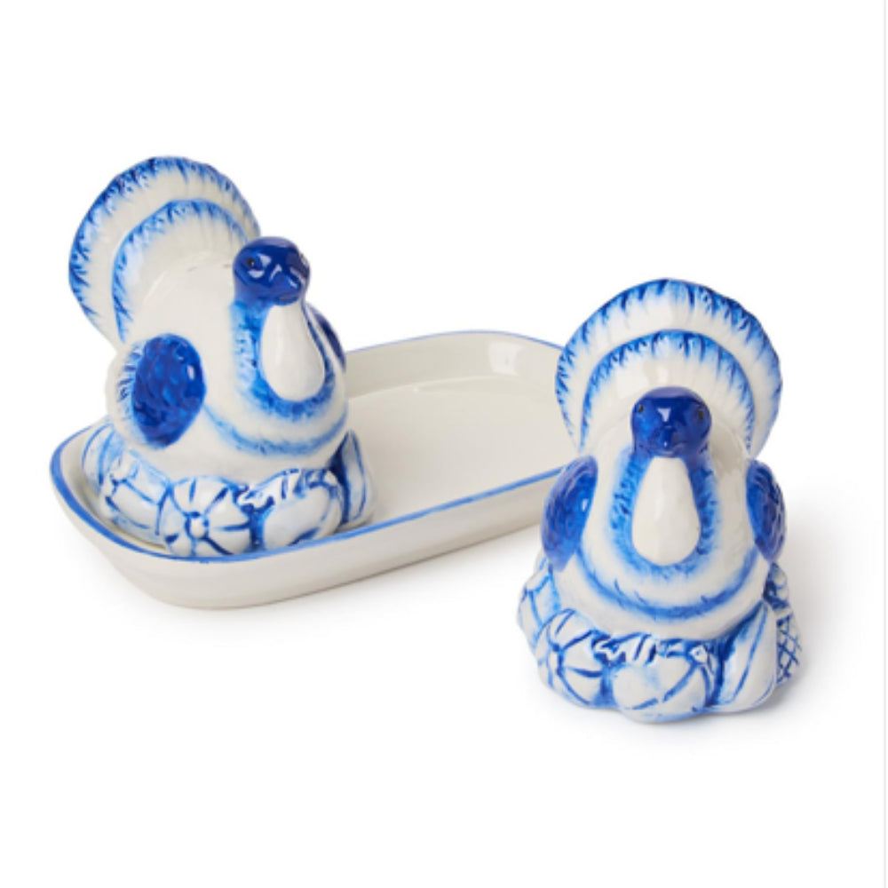 A pair of ceramic peacock figurines in a blue and white hand-painted style, with one sitting in a matching shallow dish and the other standing beside it on a white background.