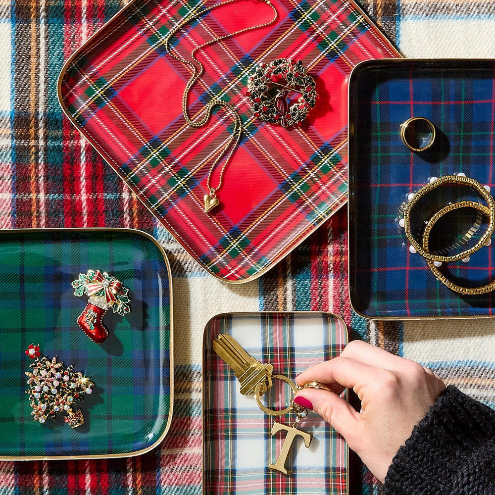 Jewelry on tartan trays with a hand holding a key-shaped brooch.
