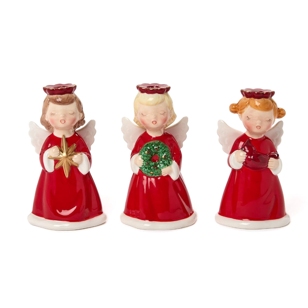 Three angel figurine candle holders in red dresses with white wings and red holos holding christmas decorations star, cardinal and wreath on a white background.