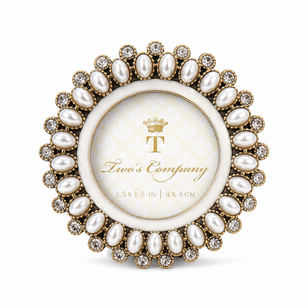 A round custom picture frame by Two Company, featuring a gold-tone metal border adorned with faux pearls and clear crystals, surrounding a central white oval insert with the brand's logo.