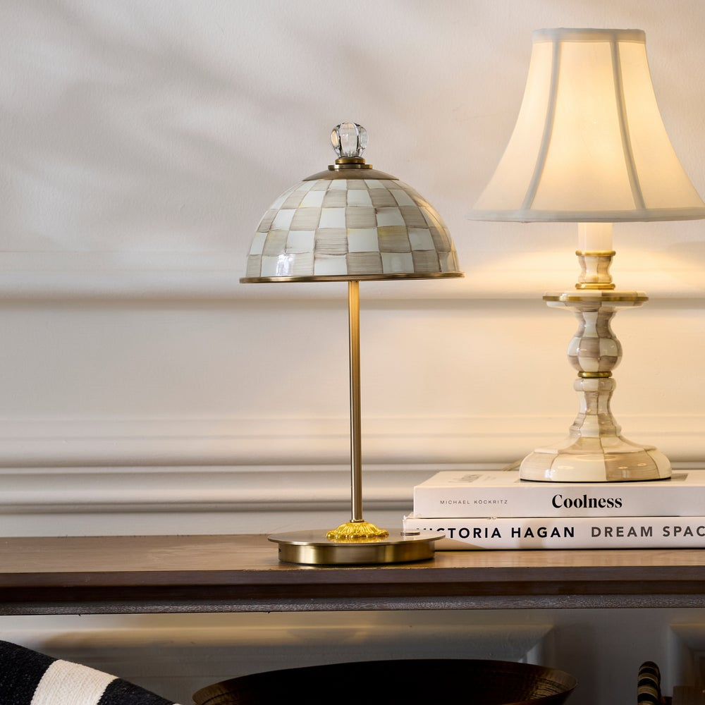 Two table lamps on a wooden surface with books underneath, against a neutral wall.