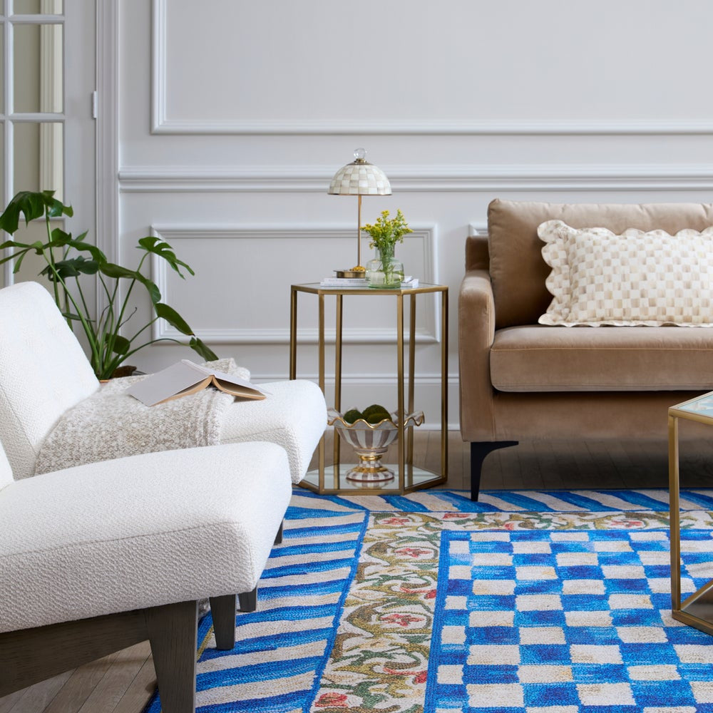 Living room with beige sofa, white armchair, and decorative rug.