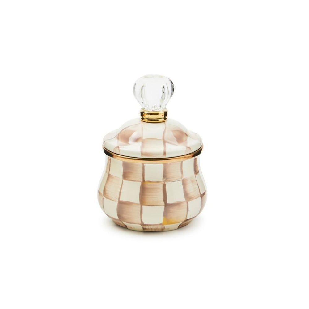 A round-shaped sugar bowl with a mocha check pattern and a lid topped with a clear glass knob and bronze-colored stainless steel trim.