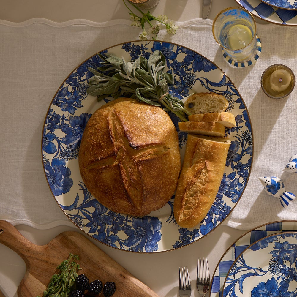 Blue and white floral-patterned plate with bread and herbs on a table setting.