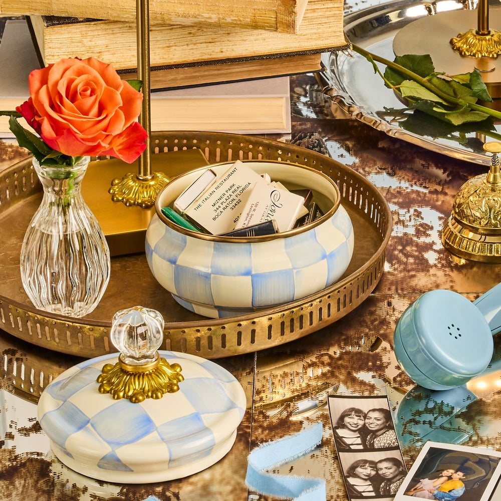 Decorative items including a checkered bowl, vase with a rose, and vintage photos on a reflective surface.