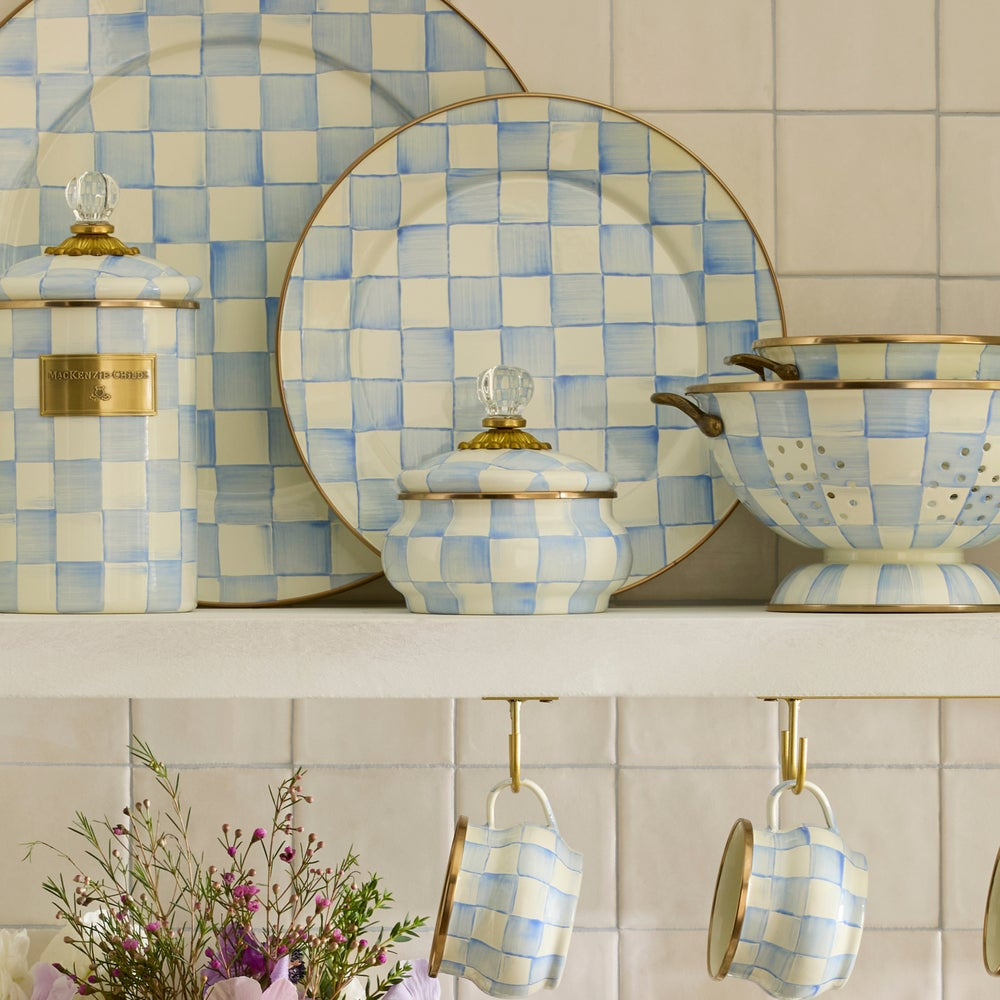 Blue checkered  plates and bowls on a shelf with a tiled wall background.