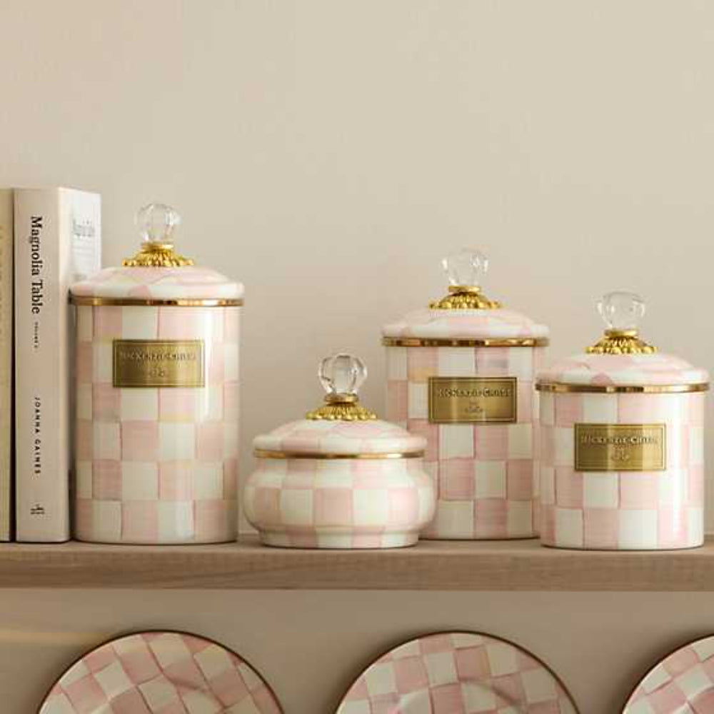 Life style photo of a decorative jar with a rosy pink and white checkered pattern and gold accents on a shelf with others.
