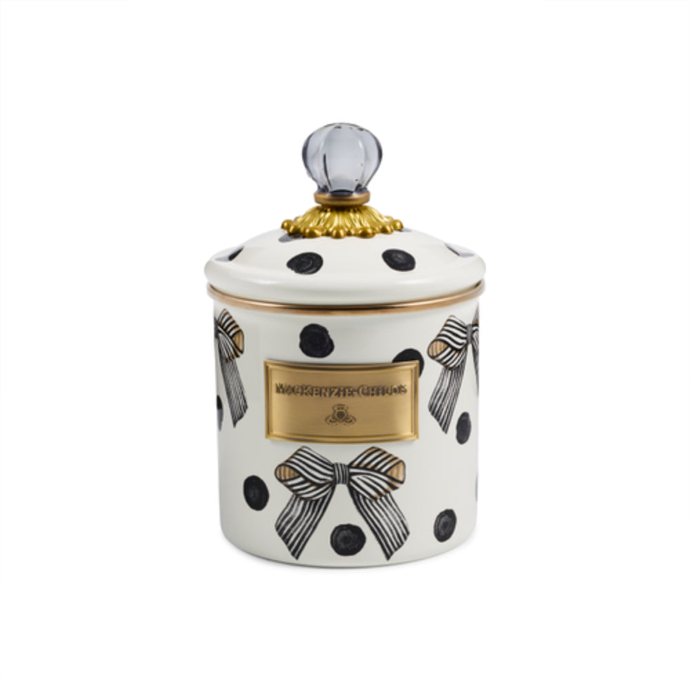 A white enamel jar with a matching lid, decorated with black polka dots, black-and-white striped bows, and a gold-tone front plaque.. The lid is topped with a clear glass finial and a gold decorative collar.