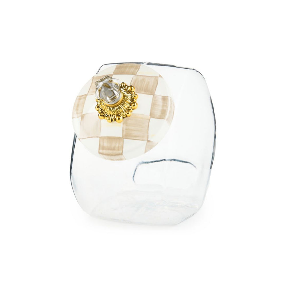 A clear glass cookie jar with a hand-painted mocha check lid and a brass bobeche on top.