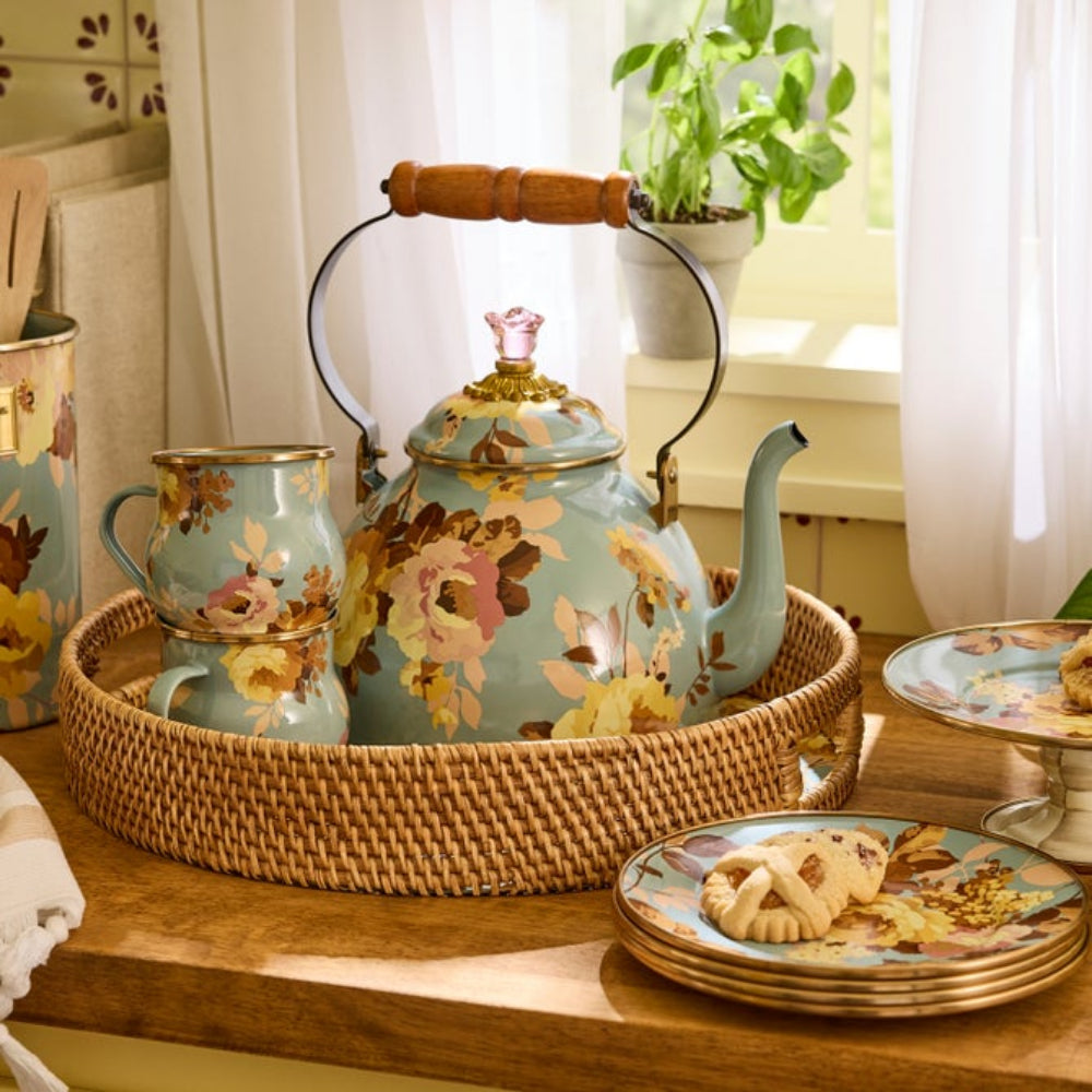 Blue decorative teapot and mug set with floral patterns in a wolven basket tray on a wooden table.