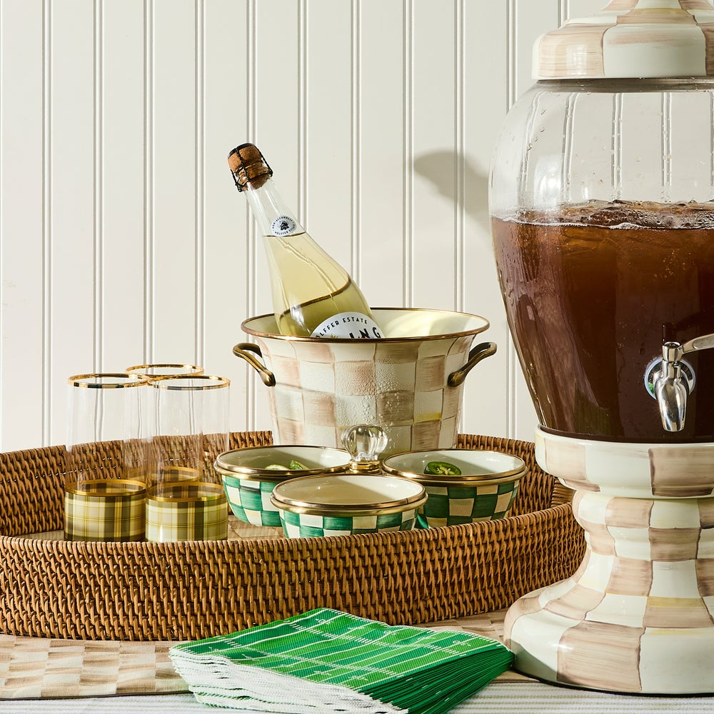 Beverage setup with a bottle of champagne, a coffee dispenser, and green and white napkins on a table.