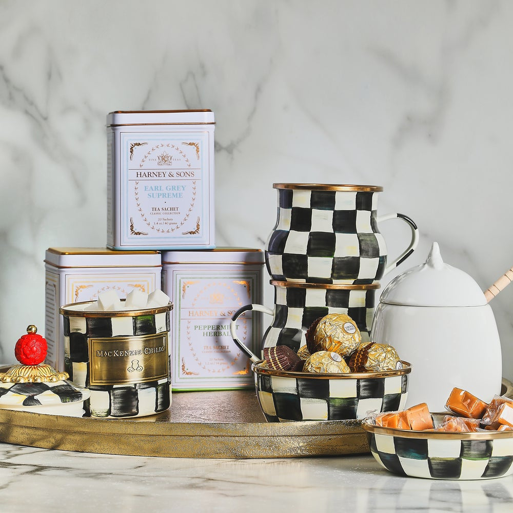 Decorative items including a checkered teapot, tins, and bowls on a marble surface.