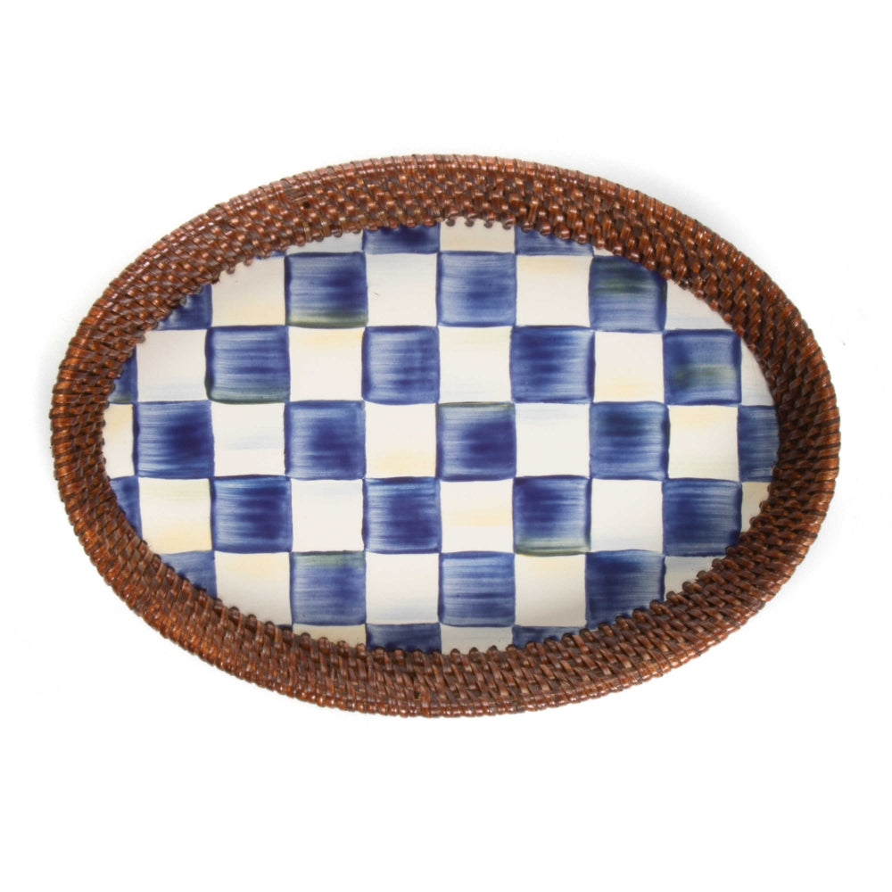 Small oval ceramic platter with royal blue and white checkered pattern surface with a woven brown rim on a white background