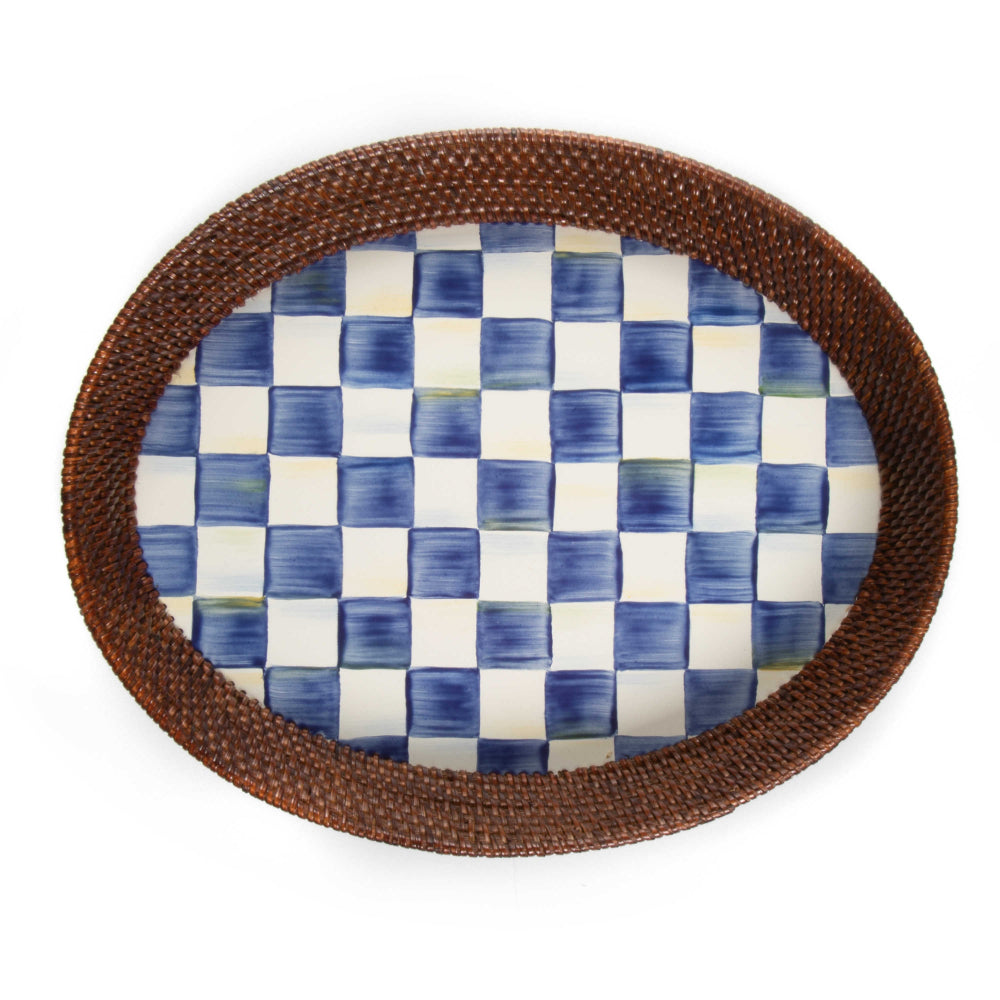 Large oval ceramic platter with royal blue and white checkered pattern surface with a woven brown rim on a white background