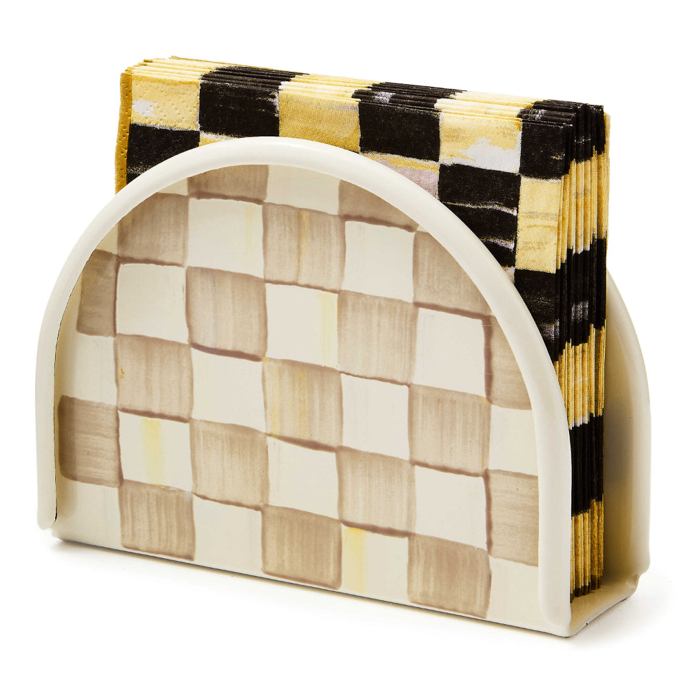 A beige and brown Mackenzie-Childs Mocha Check Napkin Holder made of enameled steel with a hand-painted, coffee-colored check pattern with yellow and black check napkins in it. 