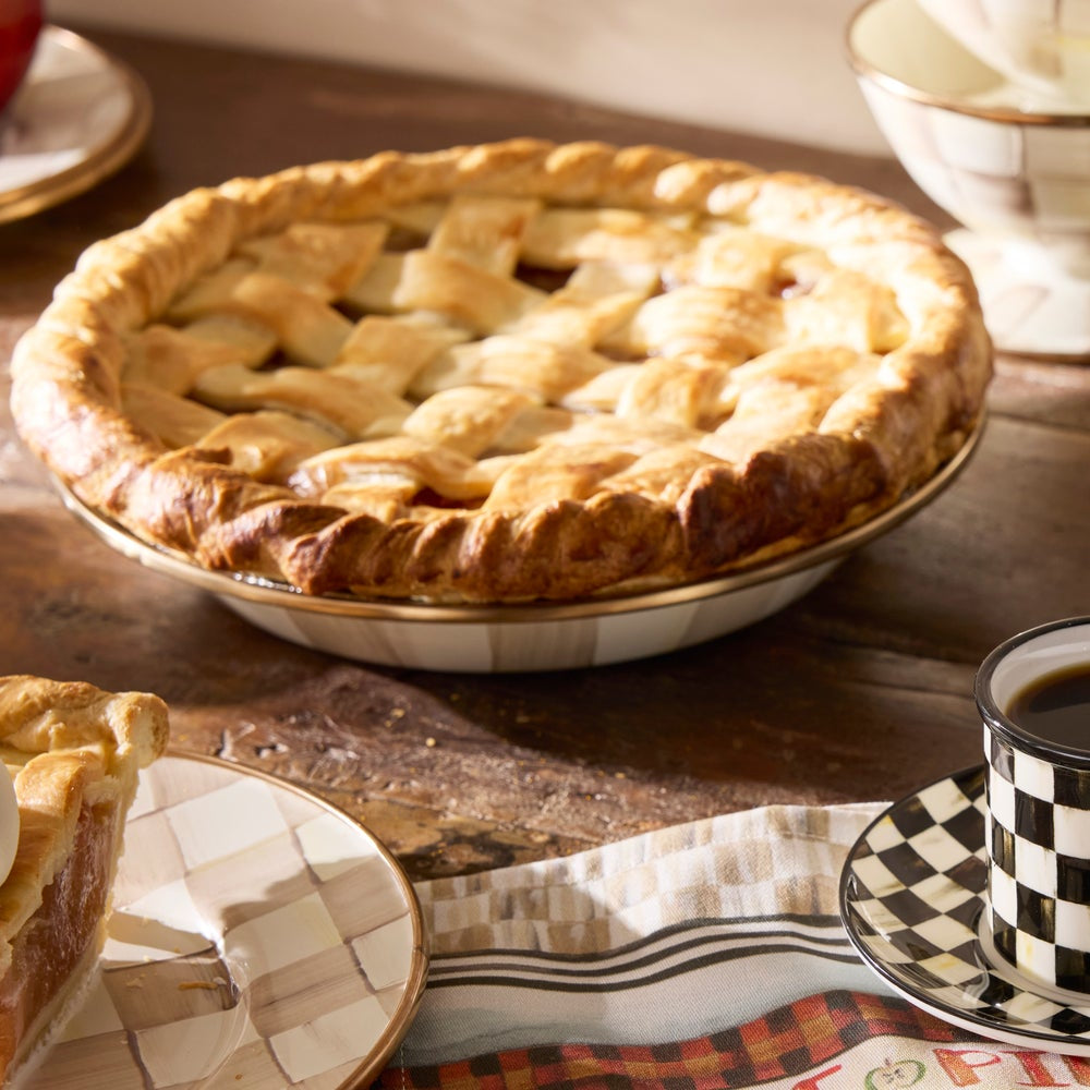 Baked apple pie on a wooden table with a cup of coffee and plaid napkin.